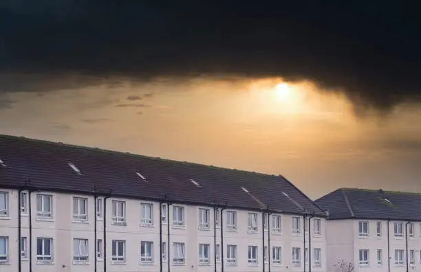 Poor council housing estate now abandoned and derelict under dark depressing storm sky