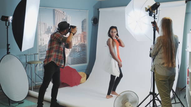 istock Beautiful african model posing for photo shoot while assistant adjusting the lighting 1203333436
