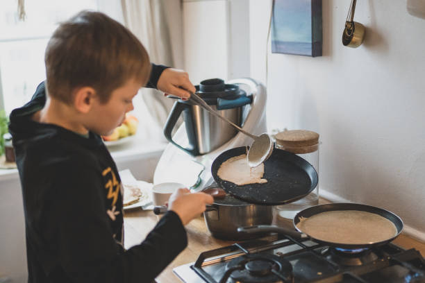 istock Young boy frying pancakes 1203335629