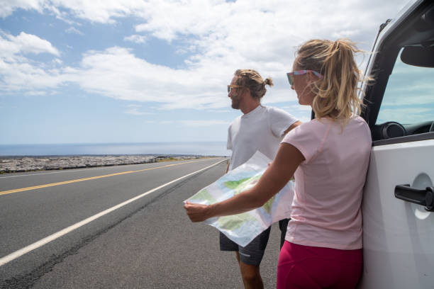 istock Young couple outside car looking at road map for directions 1203337786
