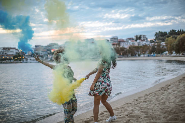istock Friends running on a beach with smoke bombs 1203338043