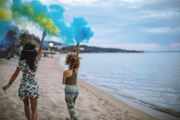 istock Friends running on a beach with smoke bombs 1203338216