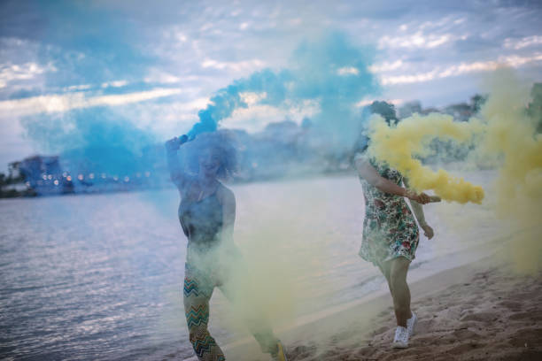 istock Friends running on a beach with smoke bombs 1203338329