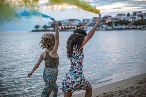 istock Friends running on a beach with smoke bombs 1203338372