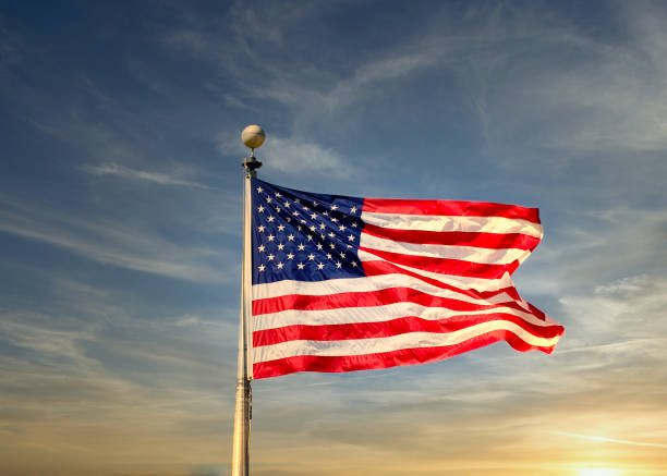 istock American Flag Blowing Sunset Sky 1203339336
