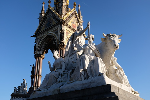 London, England - January 18, 2020: the Albert Memorial, Kensington Gardens, was completed in 1872 and faces the Royal Albert Hall. Designed by Sir George Gilbert Scott in an elaborate gothic style, it honours Queen Victoria's husband, Prince Albert, who died in 1861 of typhoid, aged 42.  In this photograph we see a detail of the monument: a stone canopy (above a gilded sculpture of Prince Albert, not seen here); below is a stone frieze known as the Frieze of Parnassus depicting famous composers, writers, artists, and architects.  Surrounding the monument at each corner are sculptures representing Europe (seen in this photograph), America, Africa, and Asia.  There are also sculptures depicting agriculture, engineering, manufacture, and commerce, as well as angels, among others.