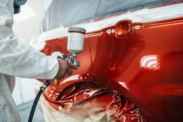Car painting Man with protective clothes and mask painting car using spray compressor. paint stock pictures, royalty-free photos & images