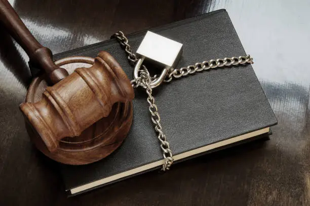 Photo of Book with judge gavel, chain and padlock