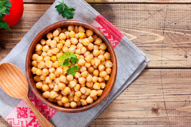 istock Boiled chickpeas in a wooden bowl on a wooden table, top view, horizontal, copy space 1203349929
