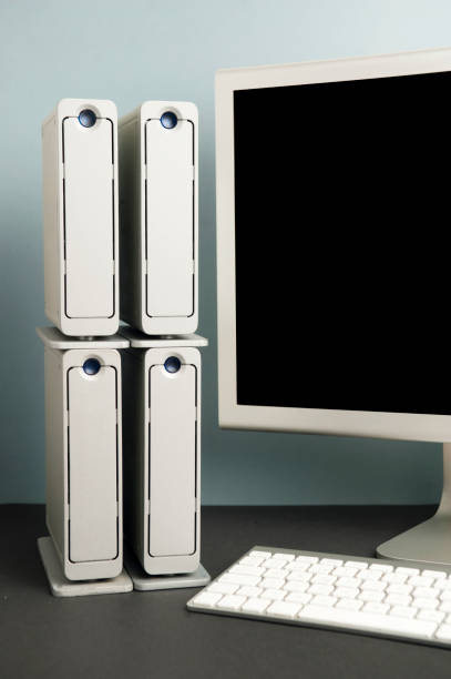istock computer security concept, four hard drives with partial view of computer monitor and keyboard. blue gray background black table 1203352272