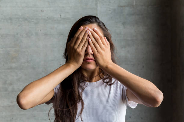 istock Young Woman Covering Eyes with Hands 1203352587