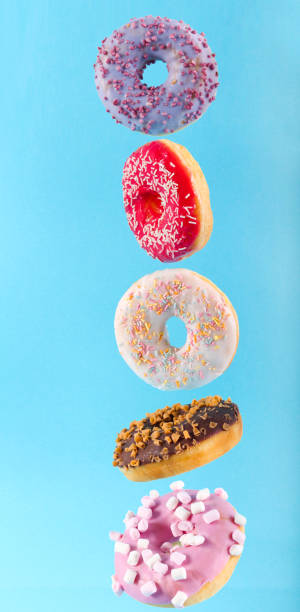 istock Flying donuts with colorful glaze over blue background 1203356854