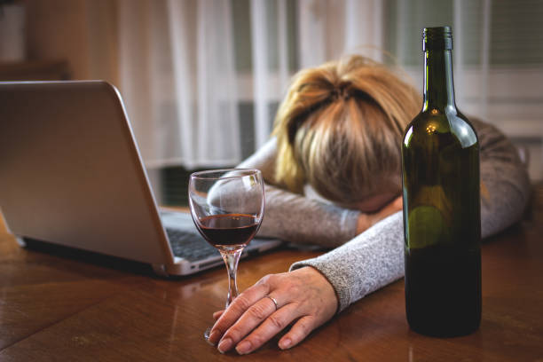 donna ubriaca con portatile aperto che dorme sul tavolo dopo aver bevuto alcolici - addiction internet computer working late foto e immagini stock