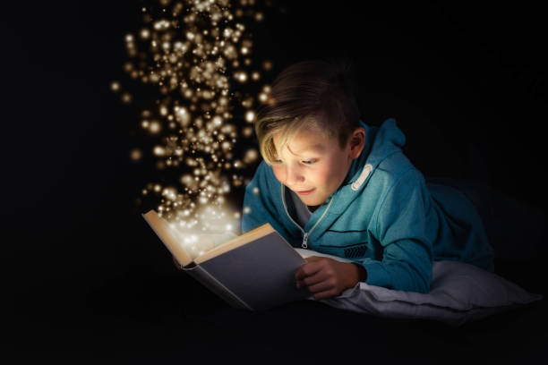 金髪の少年は、魔法の物語の本を読んで - 好奇心 ストックフォトと画像