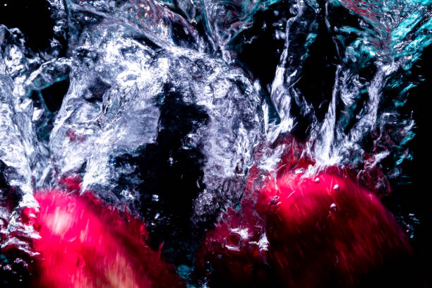 istock two apple fell into the water by raising bubbles. On a black background 1203365455