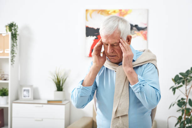 istock Tired senior man in blue shirt touching his temples while feeling headache 1203365597