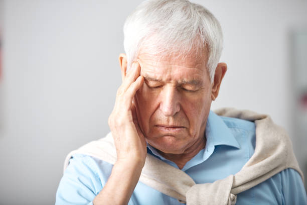 istock Sick senior man with whte hair and closed eyes touching head 1203365607