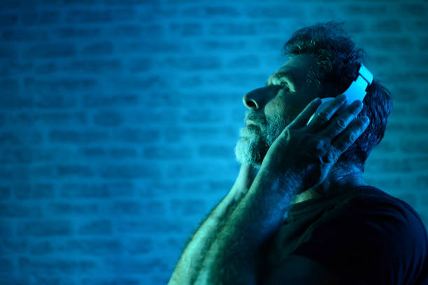 istock Mature bearded man Enjoying his favorite music, copy space. Side view. Neon light. 1203369163