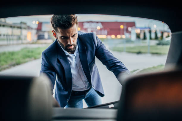 istock Businessman is  packing luggage in a car trunk 1203372084