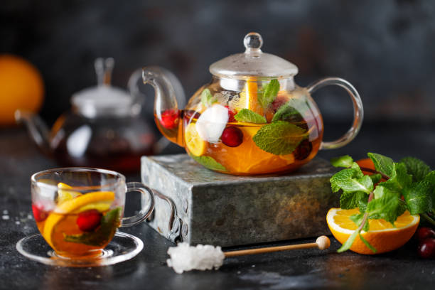 istock Fruit tea with mint, oranges and cranberry on dark stone background. A cup of hot tea 1203379394