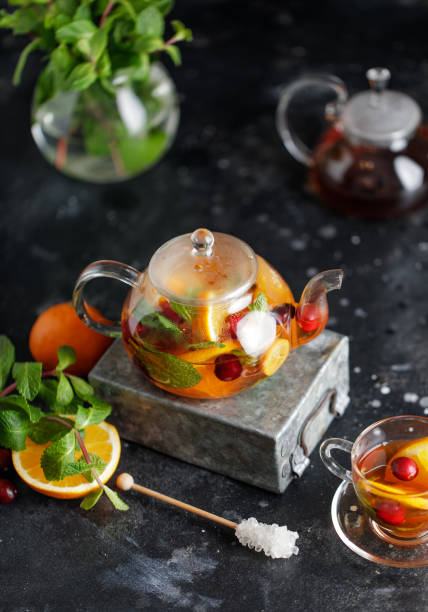 istock Fruit tea with mint, oranges and cranberry on dark stone background. A cup of hot tea 1203379520