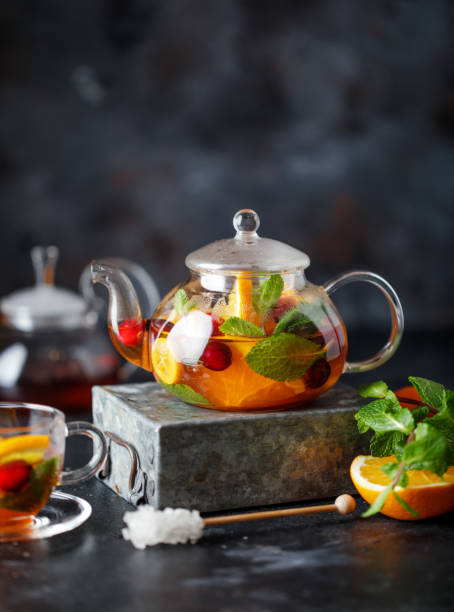 istock Fruit tea with mint, oranges and cranberry on dark stone background. A cup of hot tea 1203379536