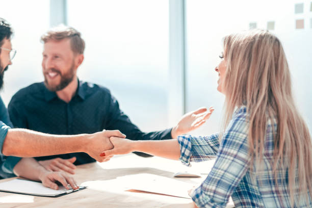 istock employer shaking hands with a young woman during the interview. 1203379647