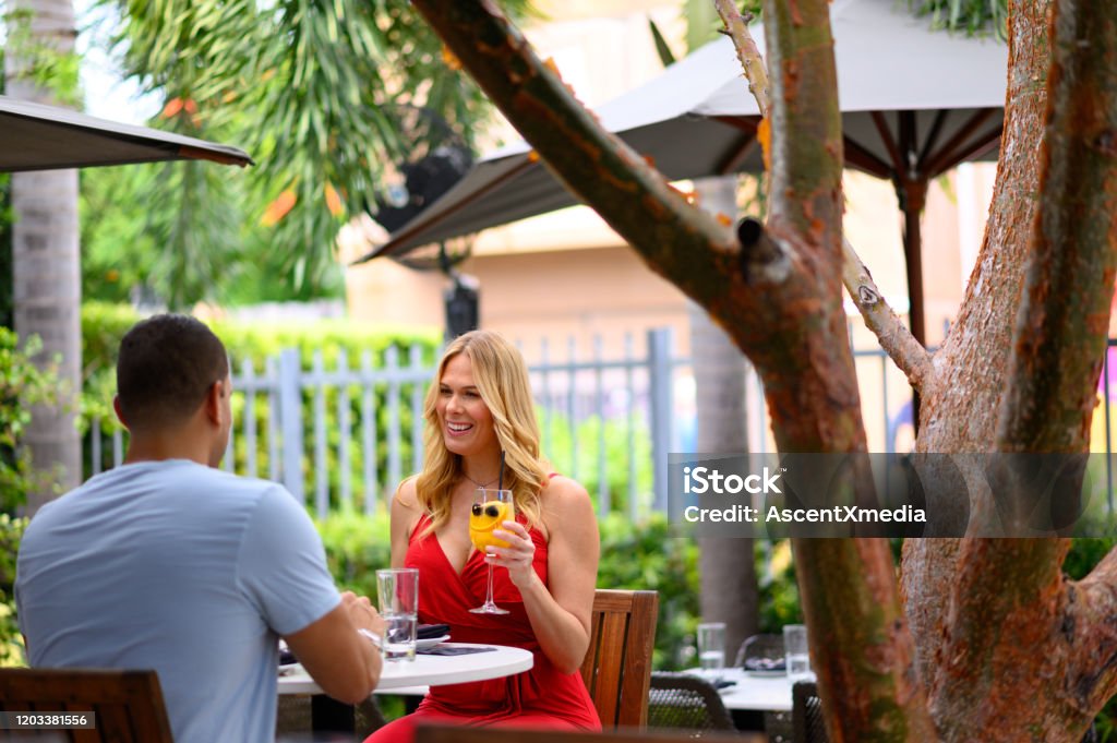 Smiling couple holding hands at restaurant Smiling beautiful blond woman holding hands with boyfriend . Couple is enjoying weekend at restaurant. They are bonding while sitting at table. Miami Stock Photo