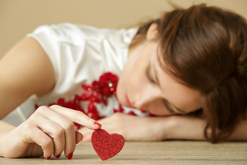 Triste mujer solitaria sosteniendo el corazón rojo.  Estar solo el día de San Valentín. Concepto de ruptura, divorcio o ruptura. photo