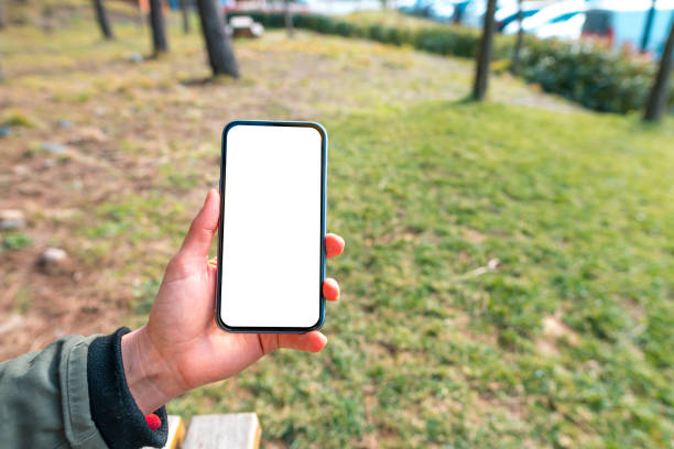 istock Hand Holding White Blank Screen Phone with Blank Screen Outdoor 1203382590