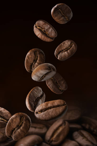 geröstete kaffeebohnen fallen auf haufen. dunkle farben - falling beans stock-fotos und bilder