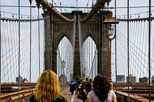 turista caminando por el concurrido puente de brooklyn en manhattan - brooklyn bridge movie famous place people fotografías e imágenes de stock