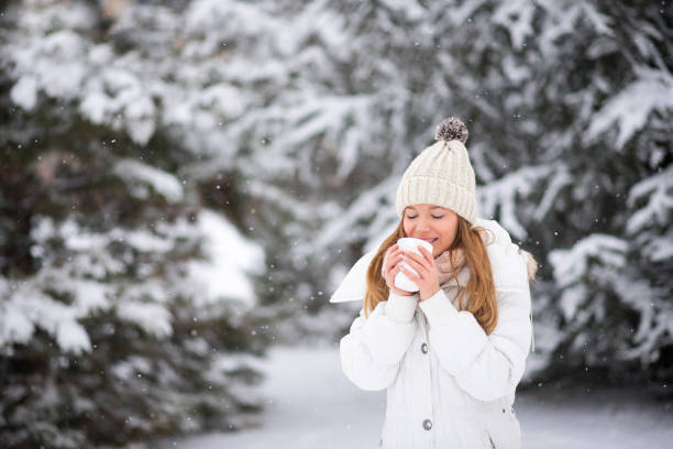 giovane donna che beve caffè, cioccolata calda, tè, fuori nella neve - snow heat adult blond hair foto e immagini stock