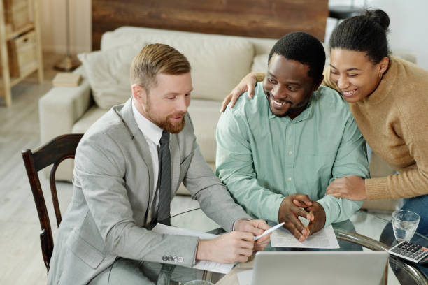 istock Cheerful ethnic couple talking to financial adviser 1203391621