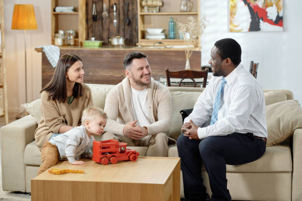 diverse man and happy family with boy having real estate consultation sitting together on sofa - family insurance agent real estate financial advisor imagens e fotografias de stock