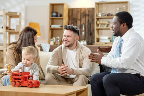 agente afroamericano che parla con una giovane coppia con un bambino di mutuo immobiliare - insurance agent expertise advice finance foto e immagini stock