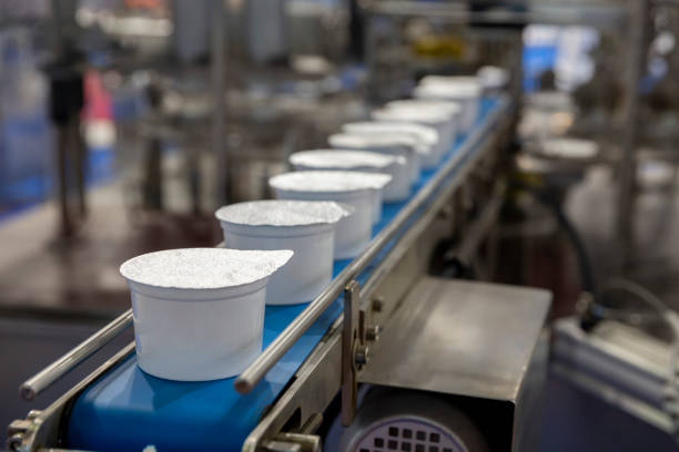 Yogurt production line White yogurt packages on a production line in a dairy farm. dairy stock pictures, royalty-free photos & images