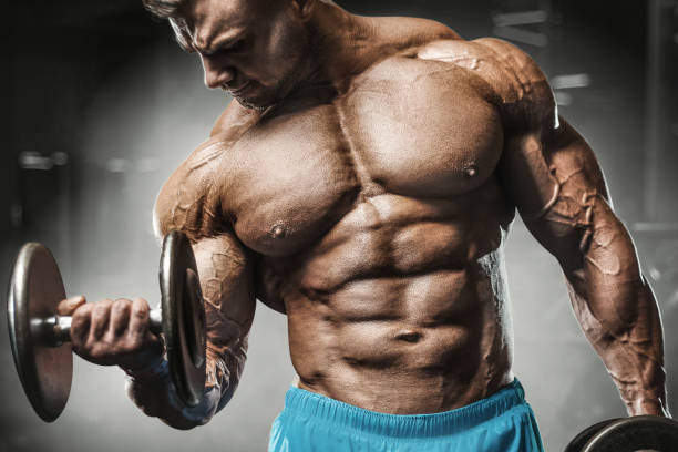 istock Bodybuilder strong man pumping up biceps muscles 1203395104