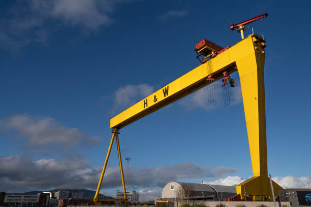 Gigantic cranes and large scale machines loom over shipyard at morning.