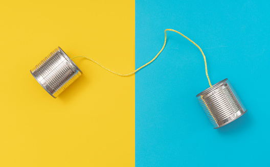 Tin can phone on yellow and blue paper backgrounds