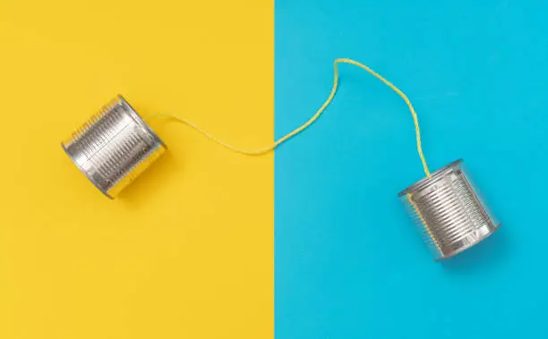 Photo of Tin can phone on yellow and blue paper backgrounds