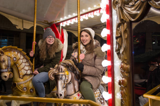istock Two happy female friends riding on carousel 1203410320