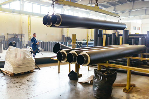 Factory worker lifting the big pipe with crane