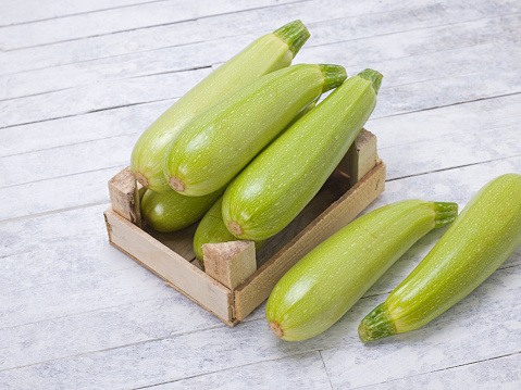 Zucchinis in wooden box on a rustic wood background