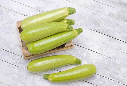 Zucchinis in wooden box on a rustic wood background