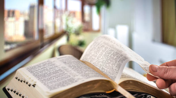 ein mann hält eine bibel und liest ein buch auf der terrasse. morgenzeit. - religious text god christianity men stock-fotos und bilder