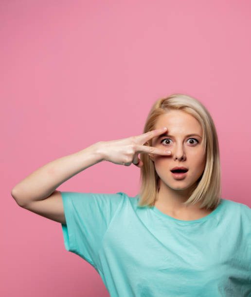 istock surprised woman show peace gesture on pink background 1203418432
