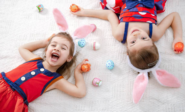 istock Happy easter Two funny cute girls with Easter eggs and Bunny ears. 1203424387