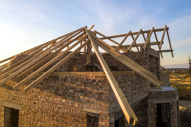 istock Private residential house with wooden roof frame structure under construction. Unfinished brick building under development. 1203426461