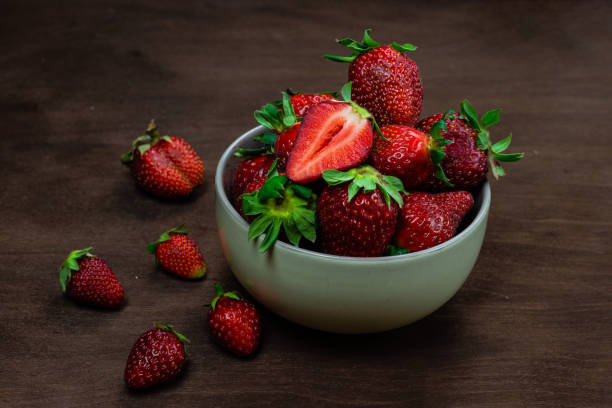 istock Fresh strawberries in ceramic bowl on dark wooden background. Selective focus. - Image 1203427210